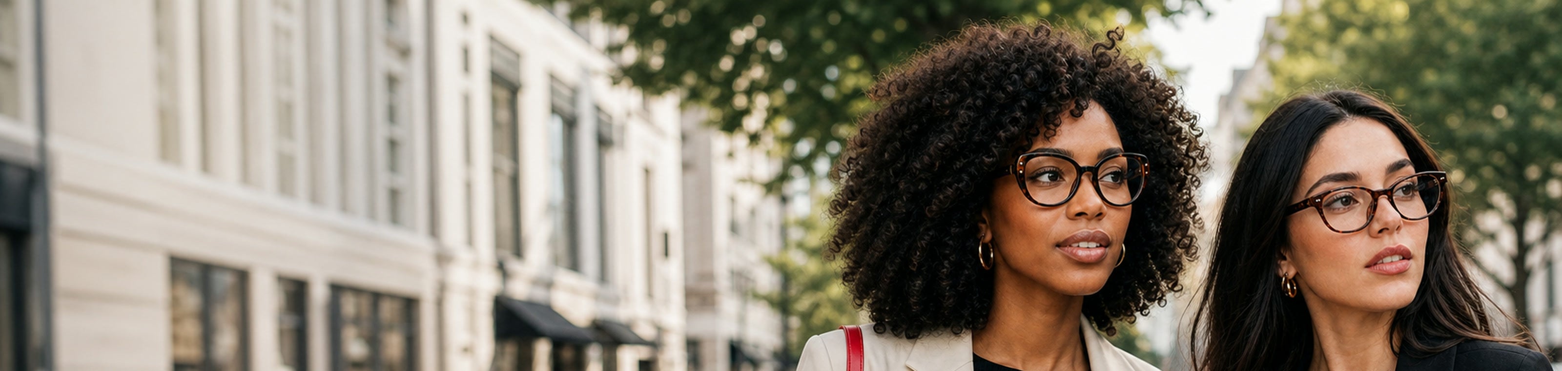 Two women wearing tortoise eyeglasses on a city street